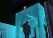 man in black jacket standing on blue lighted room