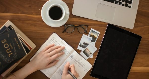 person holding ballpoint pen writing on notebook