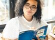 woman in white and black polka dot shirt holding blue and white book