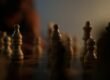 a close up of a chess board with a person in the background