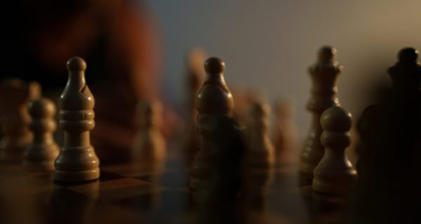 a close up of a chess board with a person in the background