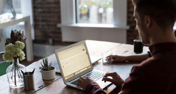 man operating laptop on top of table