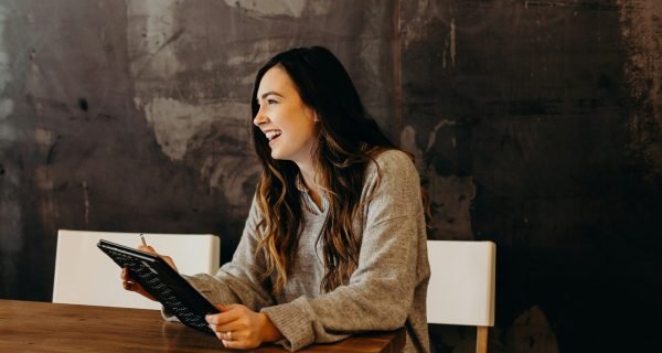 woman sitting around table holding tablet