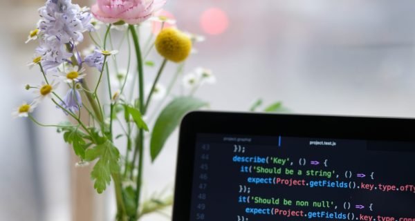 black laptop computer turned on near yellow flowers