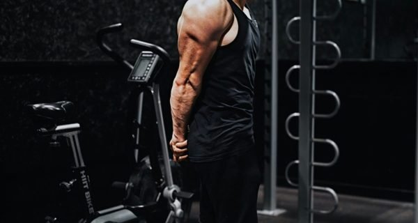 man in black tank top and black pants standing on black exercise equipment