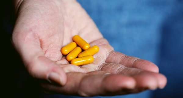 yellow medication pill on persons hand